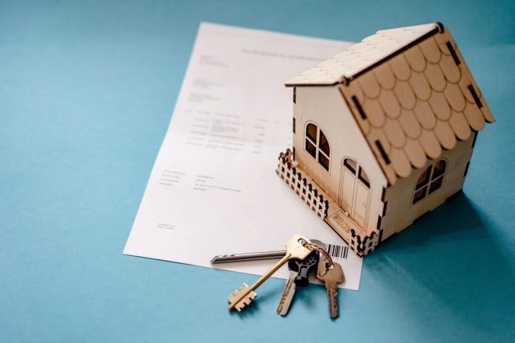 A miniature wooden house and keys on a piece of paper