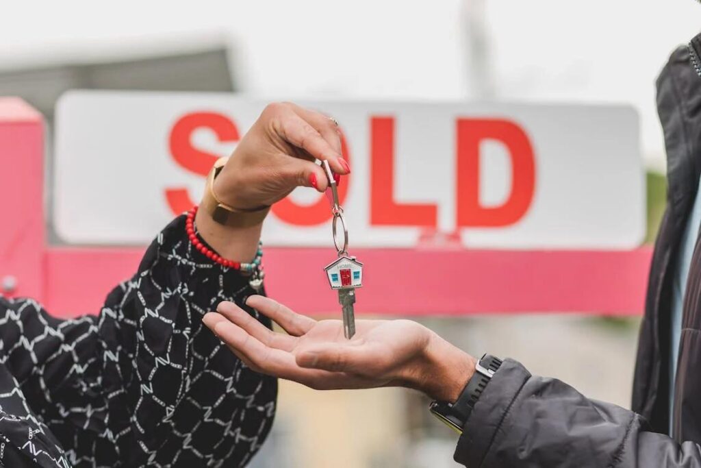 A person handing off the key to a house to the buyer