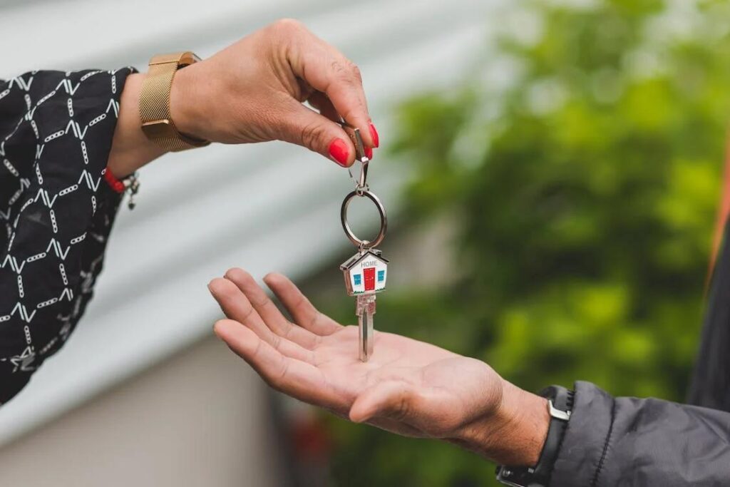 A person handing off the key to a house to the buyer