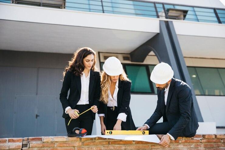 Three architects wearing helmets on a construction site