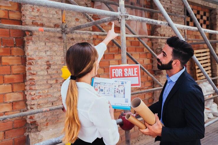 Young real estate agents discussing plans in front of a construction scaffold