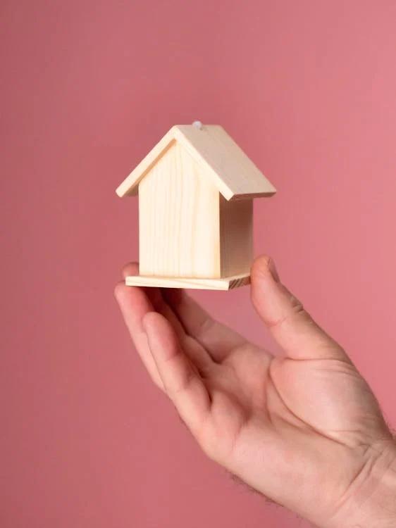 A hand holding a wooden miniature house