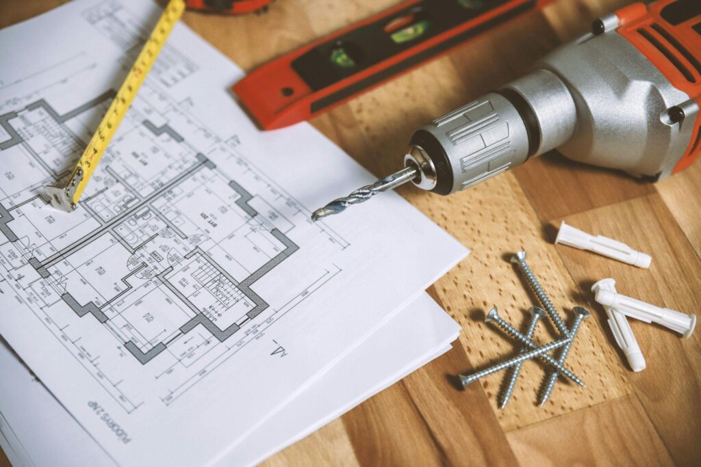 A renovation plan lies on the floor next to a drill.