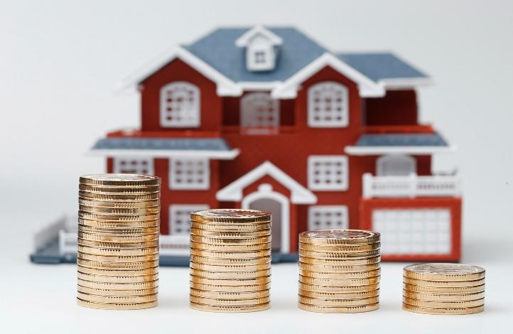 Coins Next to a Miniature House