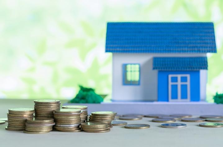 Coins Next to a Miniature Blue House