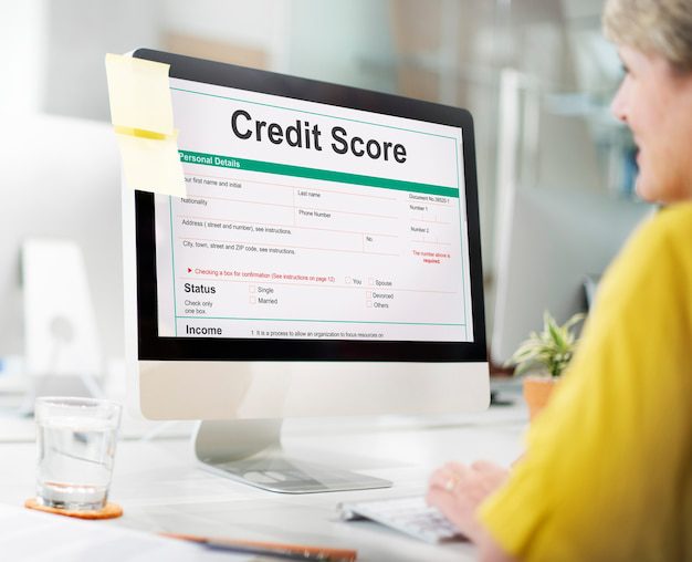 A lady working a a computer with a credit score form open