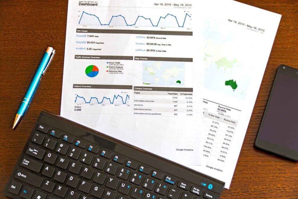 close-up of data analytics sheets with a pen, keyboard, and smartphone on a wooden desk