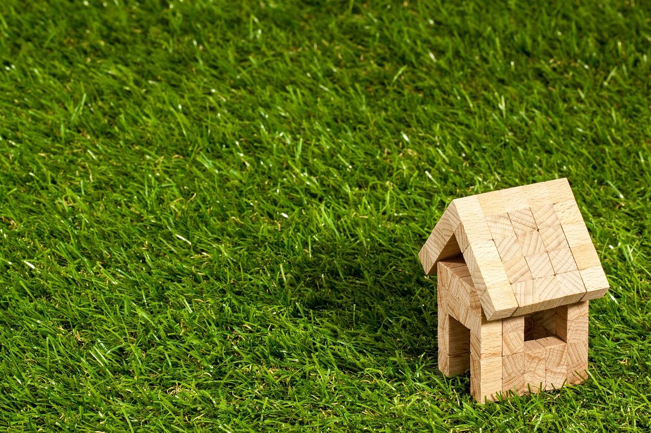 A miniature house placed on a patch of grass