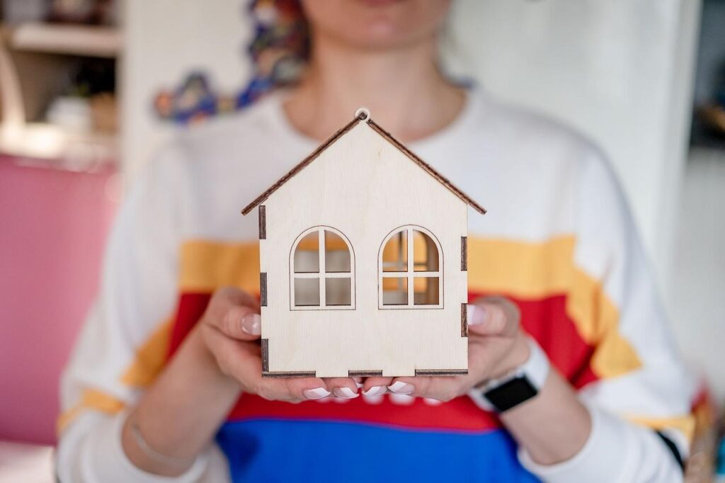 an individual holding a house figurine