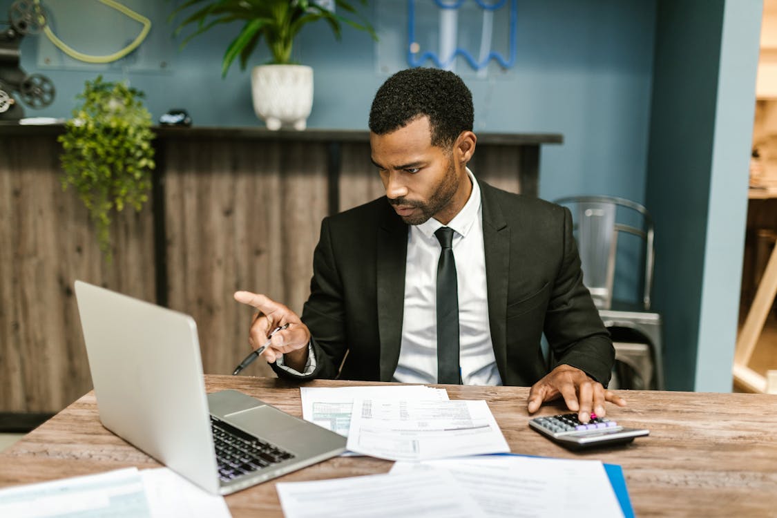 A man sitting at a table, reviewing documents, symbolizing the process of finalizing construction plans and loan agreements.