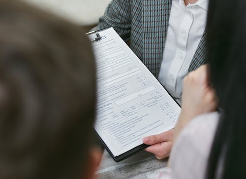 A person holding a contract document, symbolizing the process of securing a new construction loan.