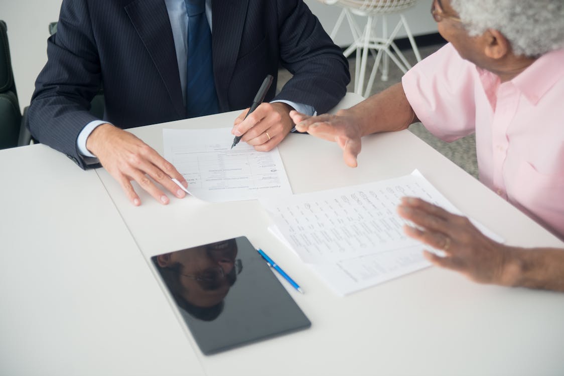 An elderly man consulting with an insurance agent, highlighting the need for insurance in new construction projects.