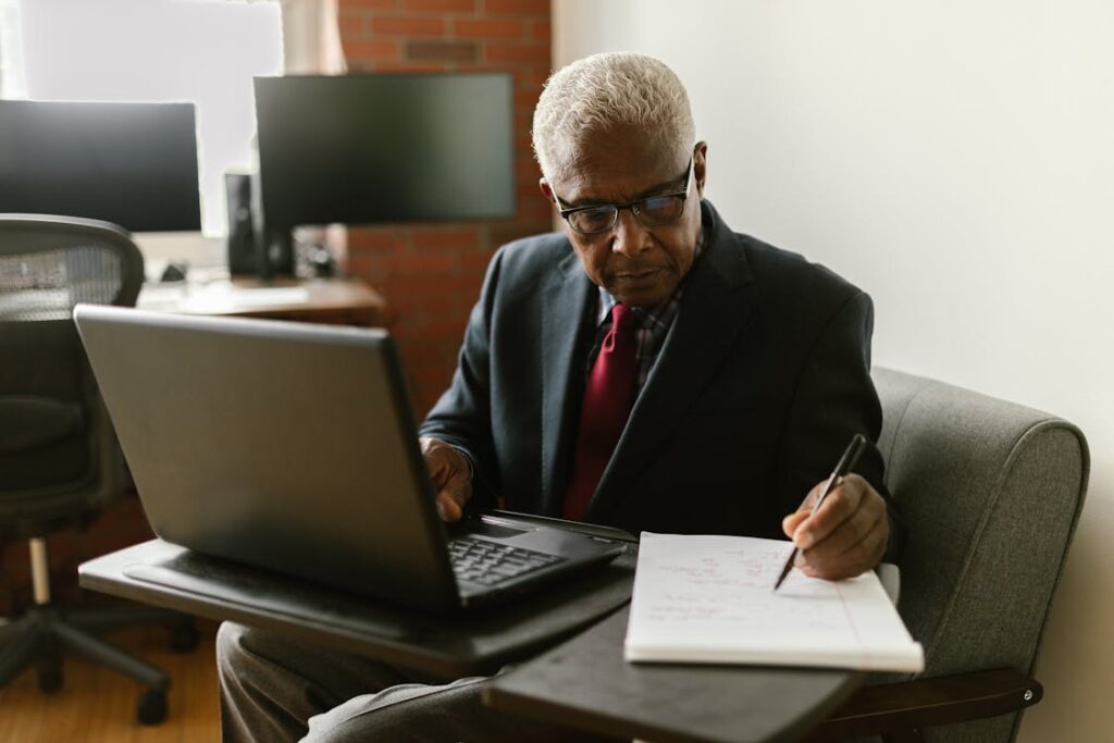 An elderly man in a black suit writing on paper, representing careful planning for new construction projects.