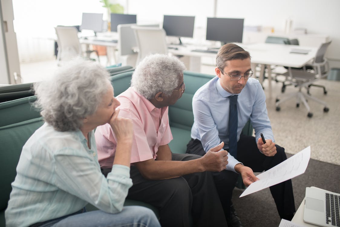 An elderly couple speaking with an, symbolizing the importance of financial and insurance planning in construction projects.