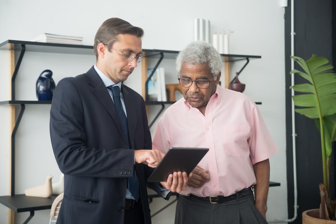 An elderly man listening to an insurance agent, representing the importance of expert advice in construction financing.