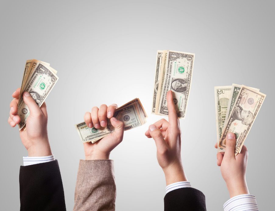 A group of people holding stacks of money, symbolizing the financial opportunities provided by bridge loans for new investors.