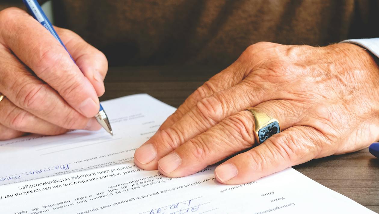 A person signing a document, symbolizing the final steps in securing a new construction loan.