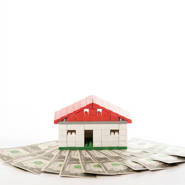 A toy house placed on a stack of cash, symbolizing real estate investment financing.