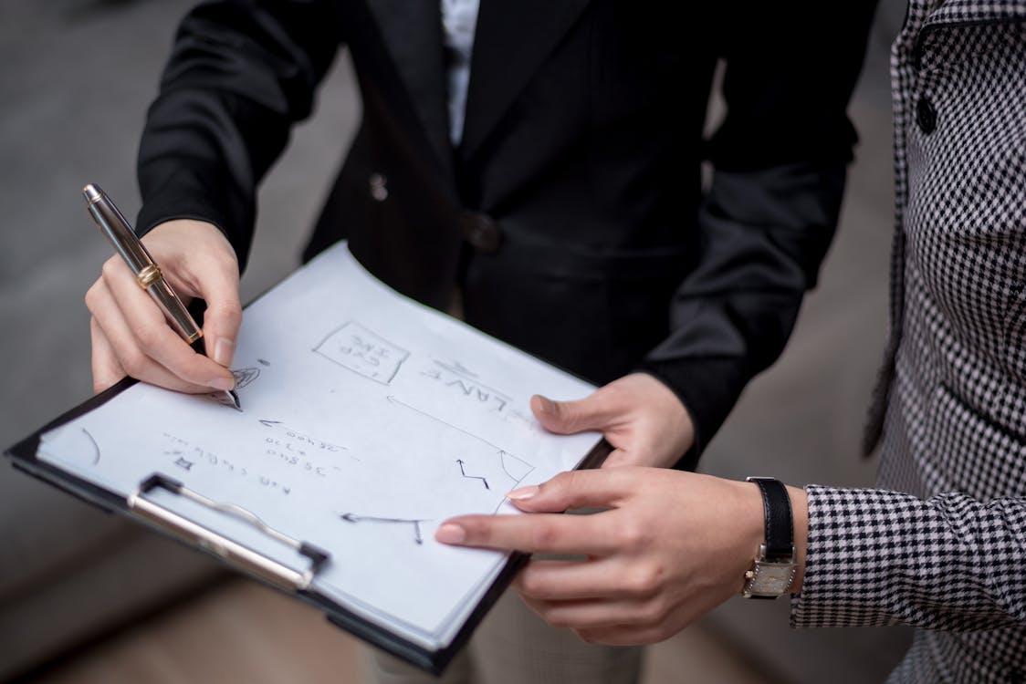 A person in a black suit writes on a document with focus, symbolizing attention to detail in investment property financing.