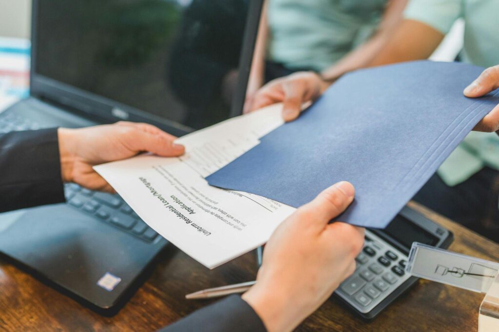 Hands exchanging contracts, symbolizing teamwork and asset-based financing in real estate.