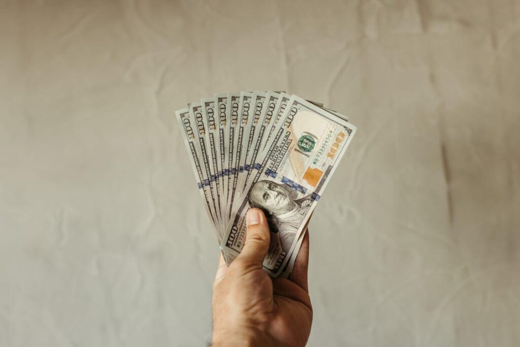 A hand holding 100-US dollar banknotes