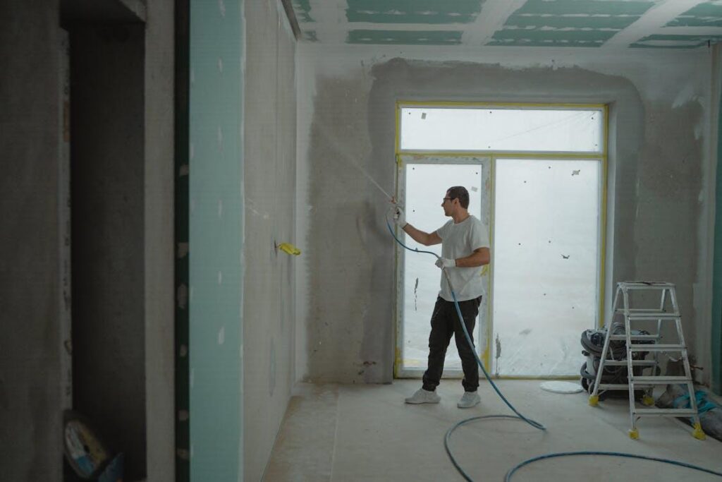 A man spray painting a room