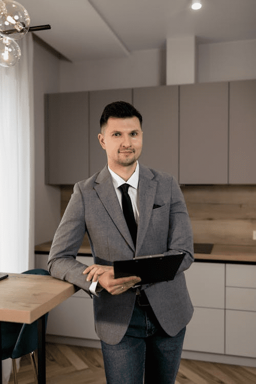 A man in a gray suit jacket holding a black folder, ready to discuss real estate development financing