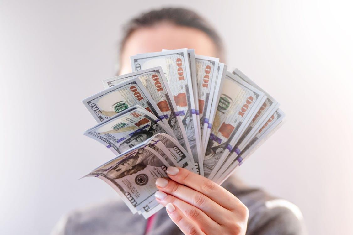 A person holding 100-US dollar banknotes