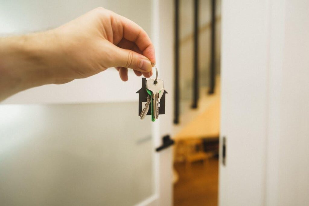 A person holding a house key with a home keychain