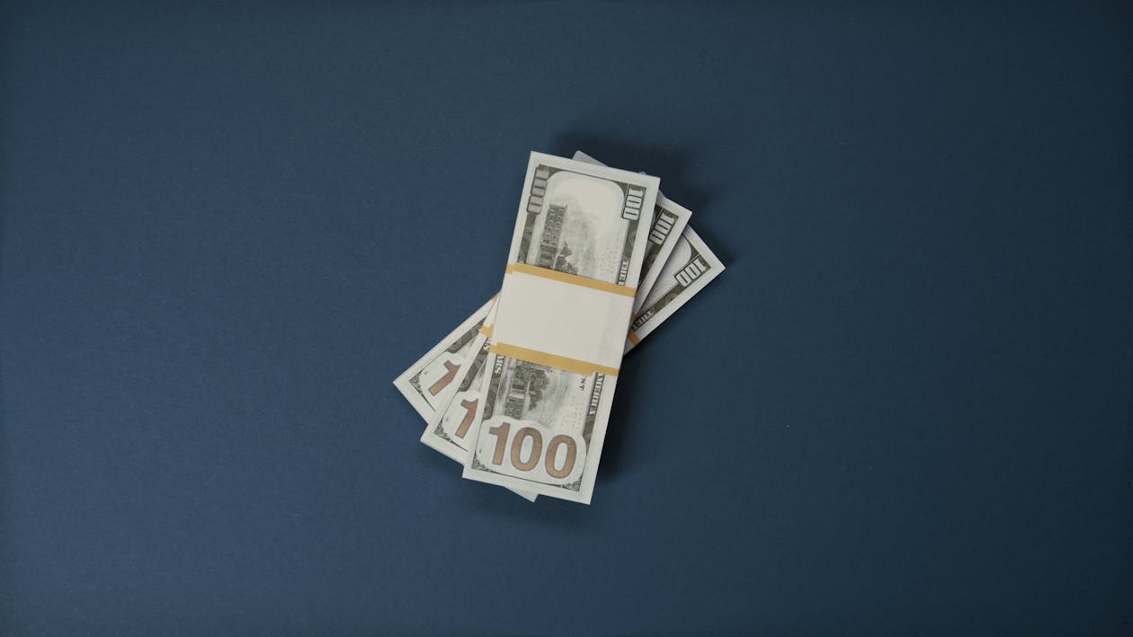 Bundles of 100-dollar US banknotes on a dark blue surface