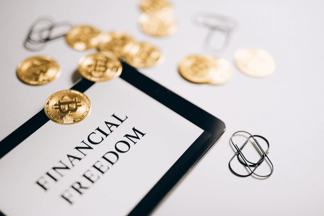 A tablet screen with text “financial freedom” written on it and some coins