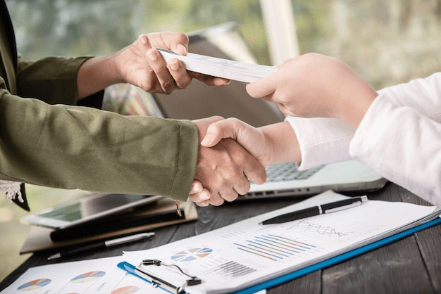 Two people shaking hands after finalizing a cash-out refinancing agreement.
