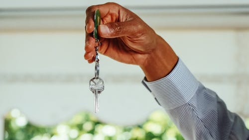 A person holding house keys, symbolizing rental property acquisition through smart financing.
