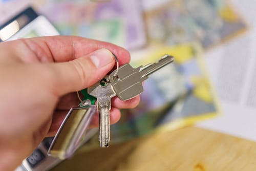 A person holding house keys, symbolizing securing a rental property loan.