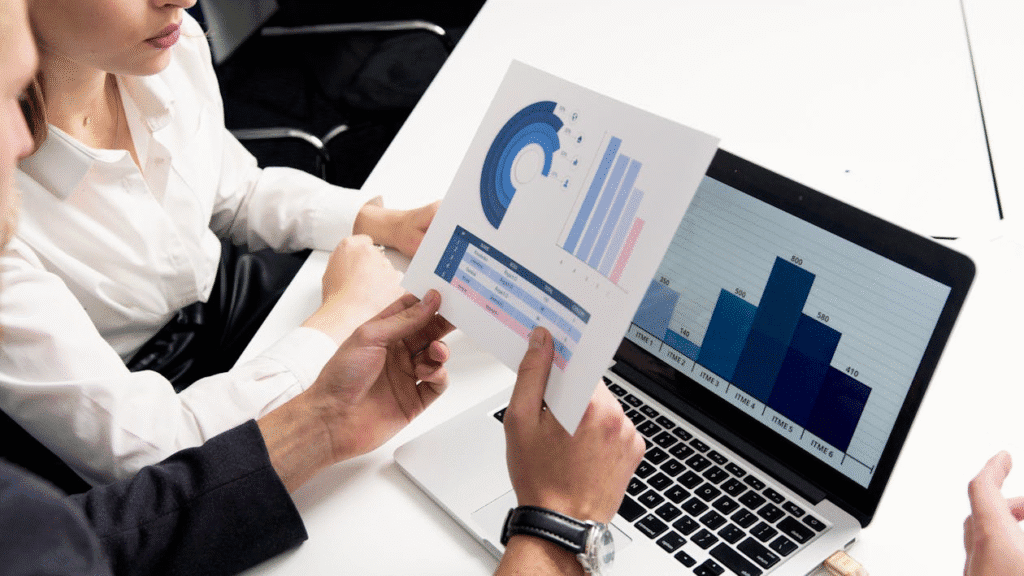 Two people looking at graphs on laptop and papers