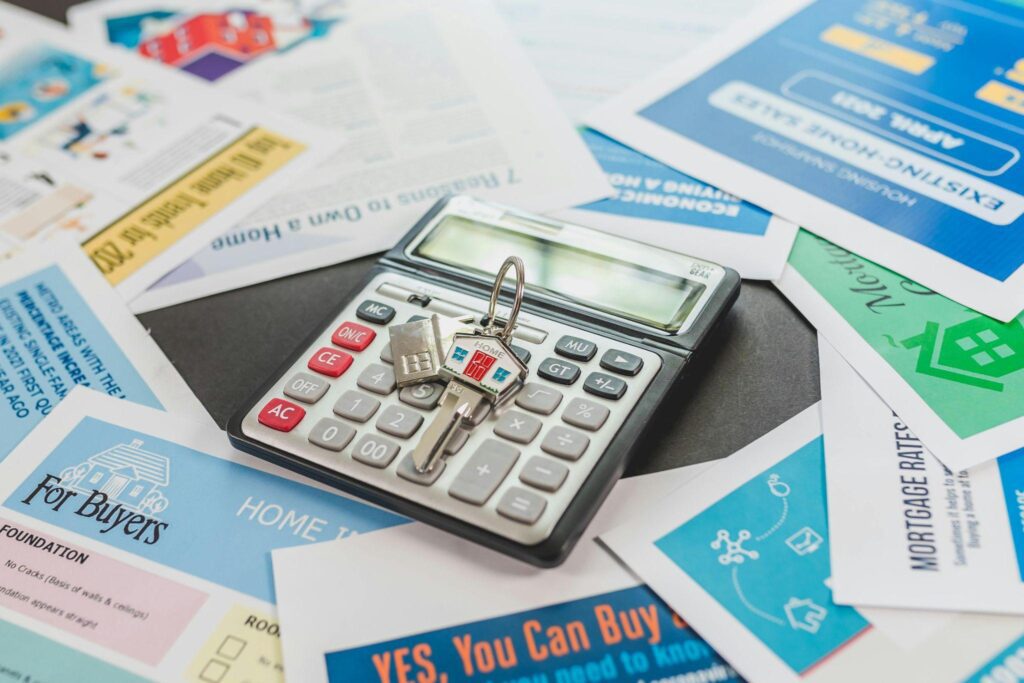A calculator with a house-shaped keychain resting on top.