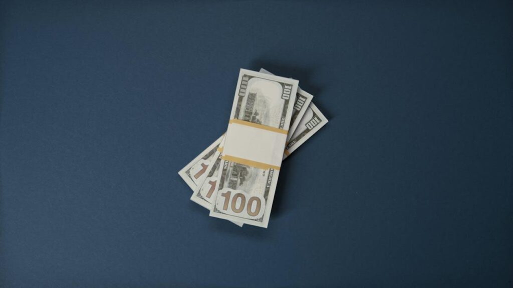 Bundles of 100-US dollar banknotes on a dark blue surface 