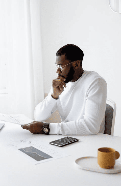 A person reviewing financial documents with a calculator and laptop