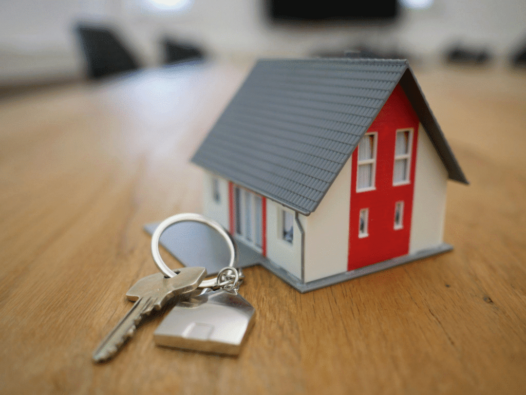 A miniature house with a house-shaped key placed beside it.