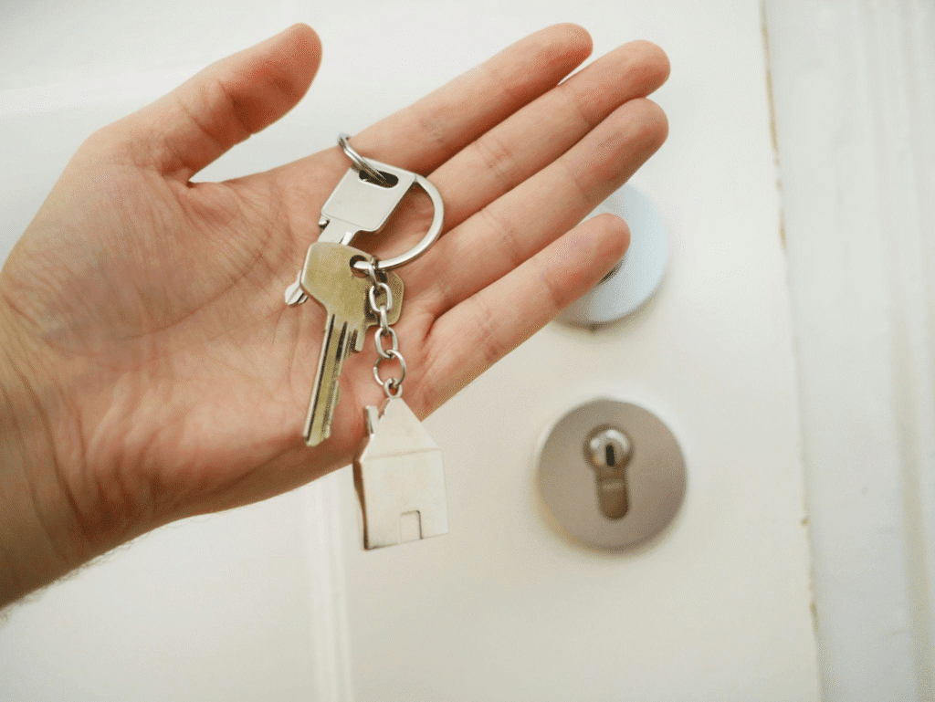 A person holding a key with a house-shaped keychain.