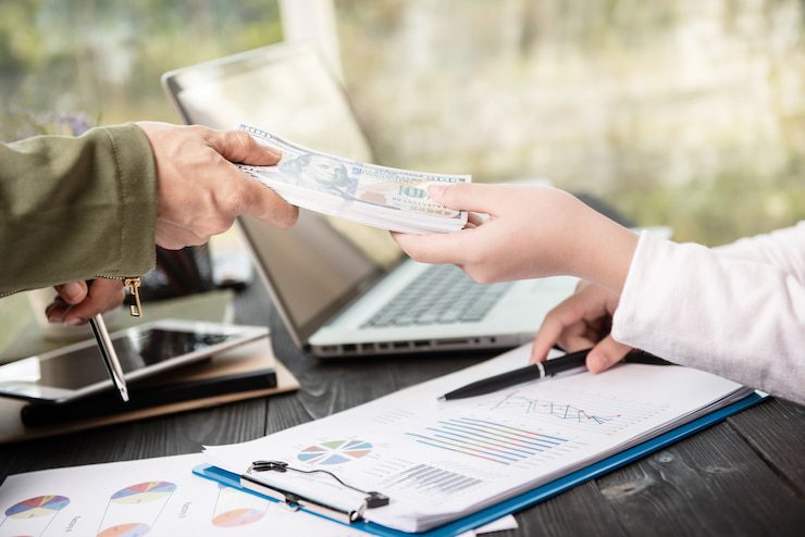 Person handing over cash, representing fast funding through private money lenders in a competitive housing market.