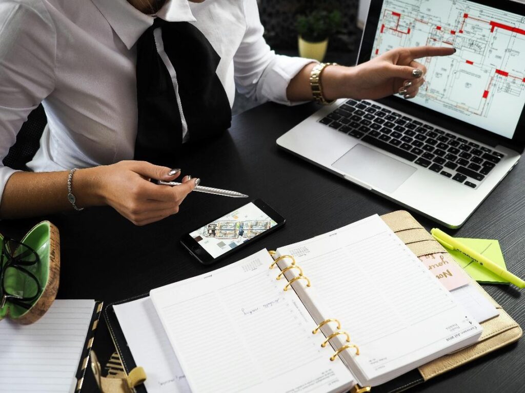 Person pointing to data on a laptop screen while discussing climate-resilient real estate investments