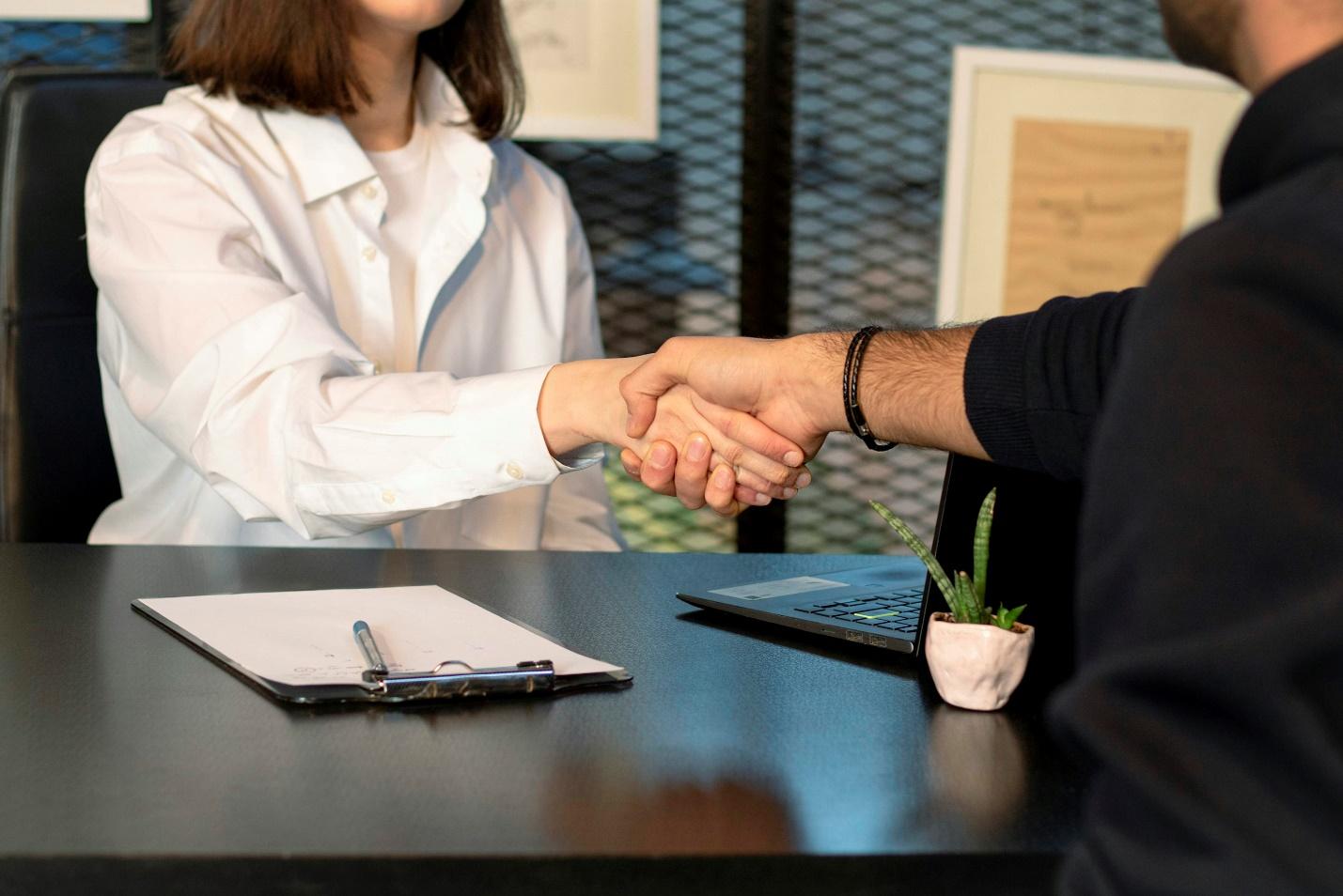 An image of two people in an office shaking hands, symbolizing the closing off on a deal.