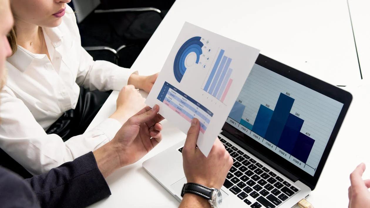 A person holding a paper in front of laptop
