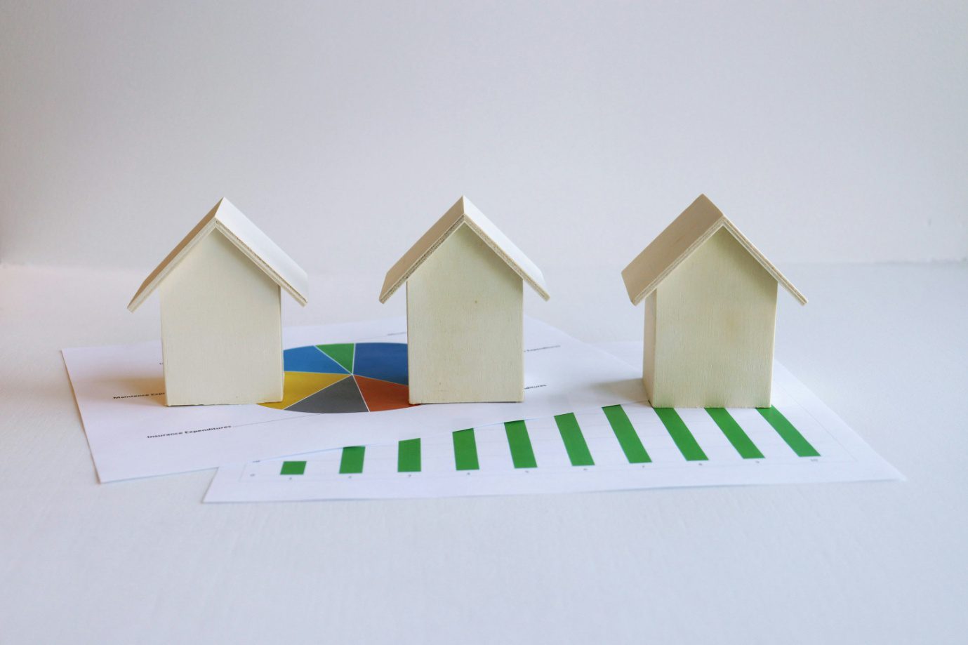 house-shaped figurines placed atop financial documents