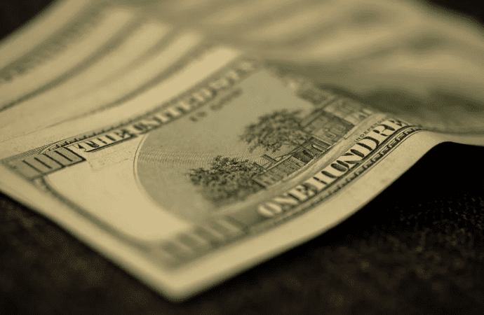 A close-up of a one-hundred dollar bill placed on a flat surface