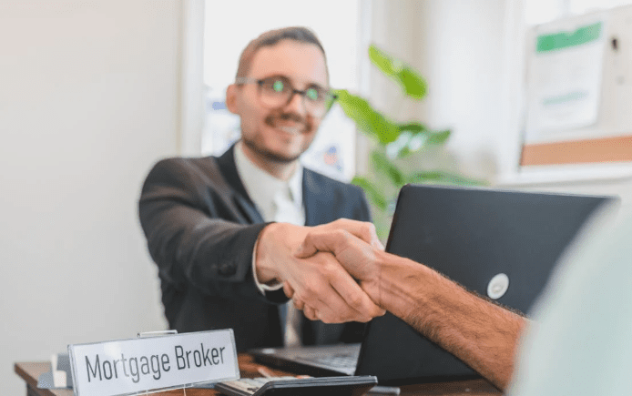 A broker shaking hands with a client across the table after closing a financial deal