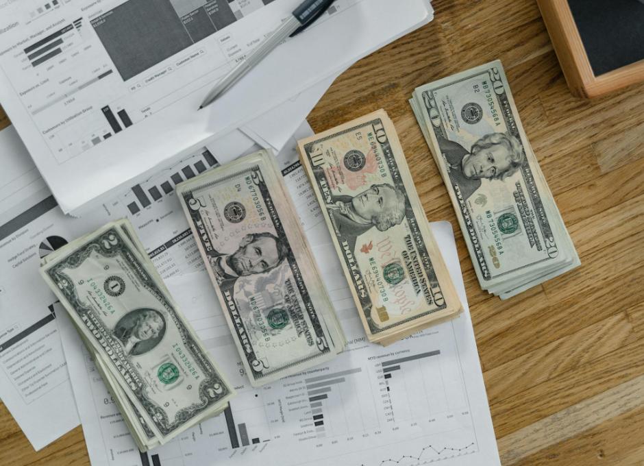 Various denominations of U.S. dollar bills are neatly stacked on financial charts