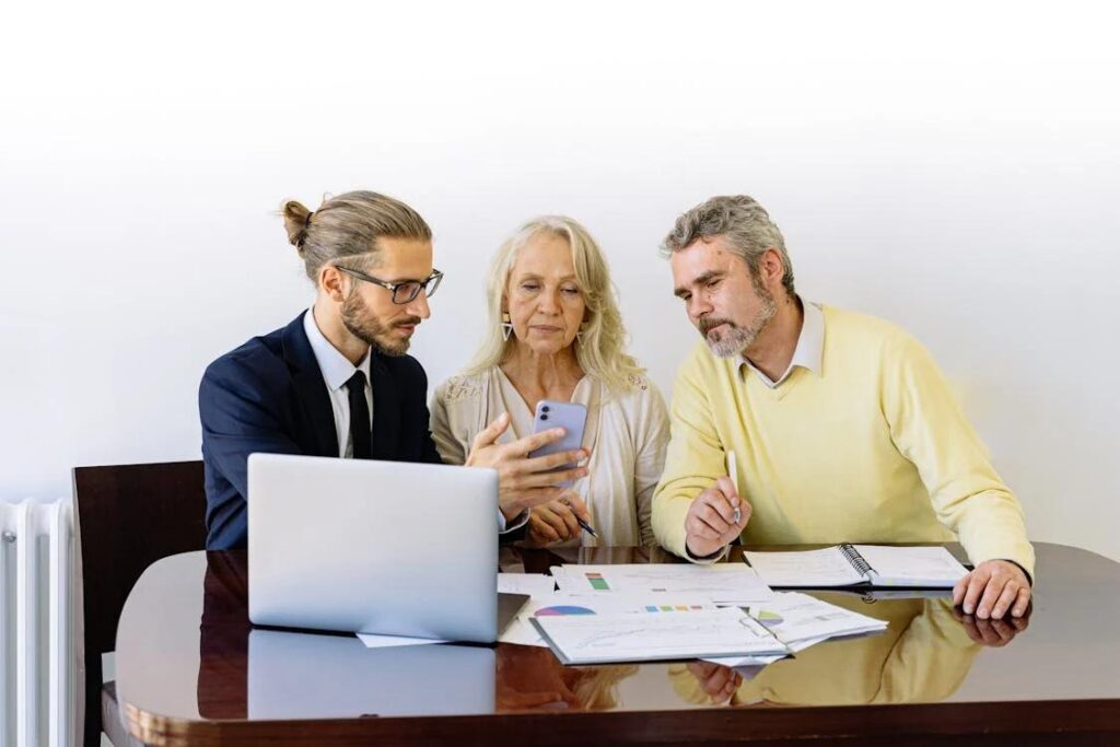 A young male financial advisor shows something on his phone to an older couple