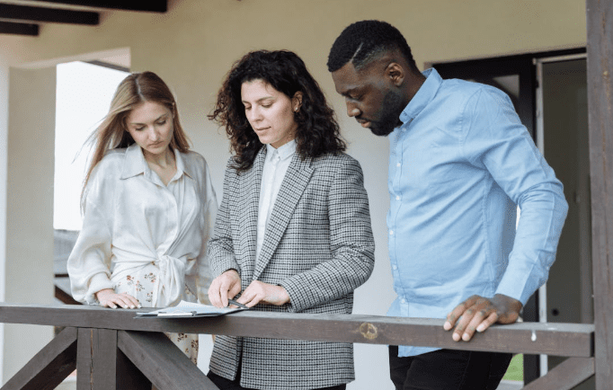 A group of professionals standing at a site, reviewing documents on a clipboard